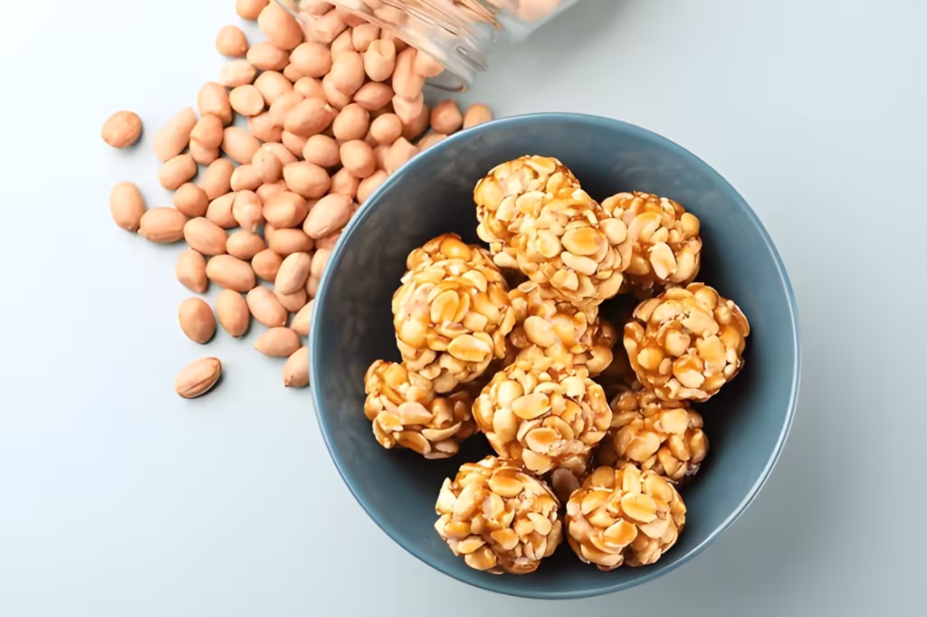 ingredients of peanut chikki including raw peanuts and homemade peanut chikki ladoos presented in a blue bowl