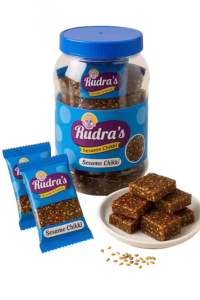 Rudras sesame chikki jar with two packets and small bowl of chikki in front